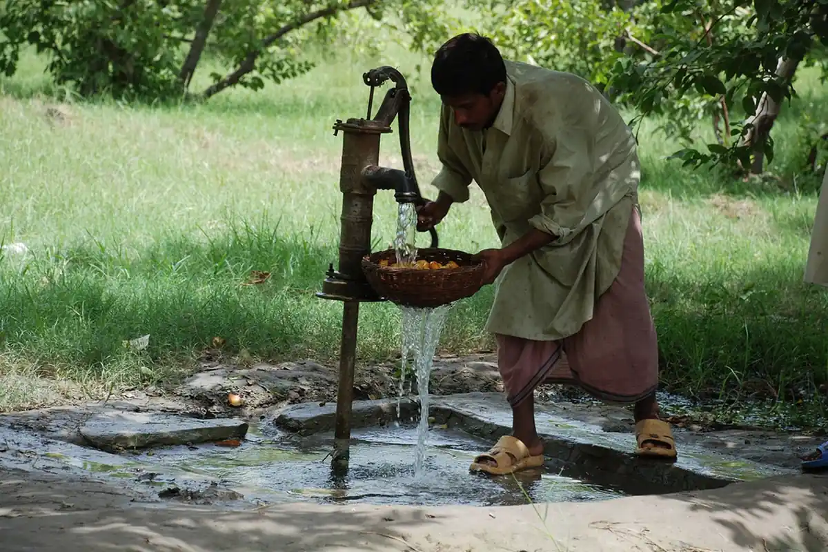 A man drawing water from a hand pump in rural Pakistan