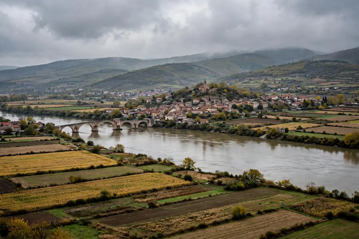 A river town and bridge in northern Bosnia under a cloudy sky