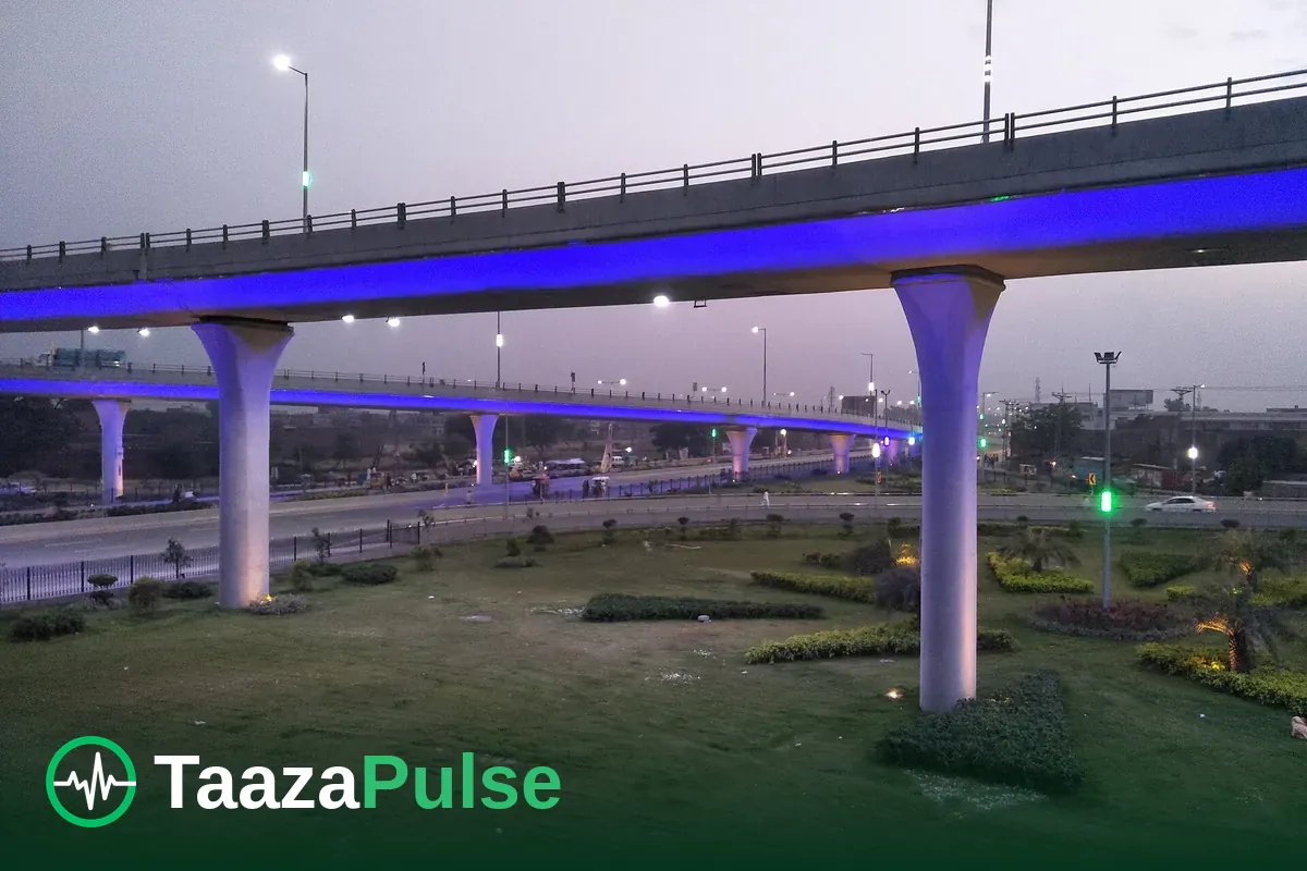 A flyover in Gujranwala at dusk, with lit roads and green verges below