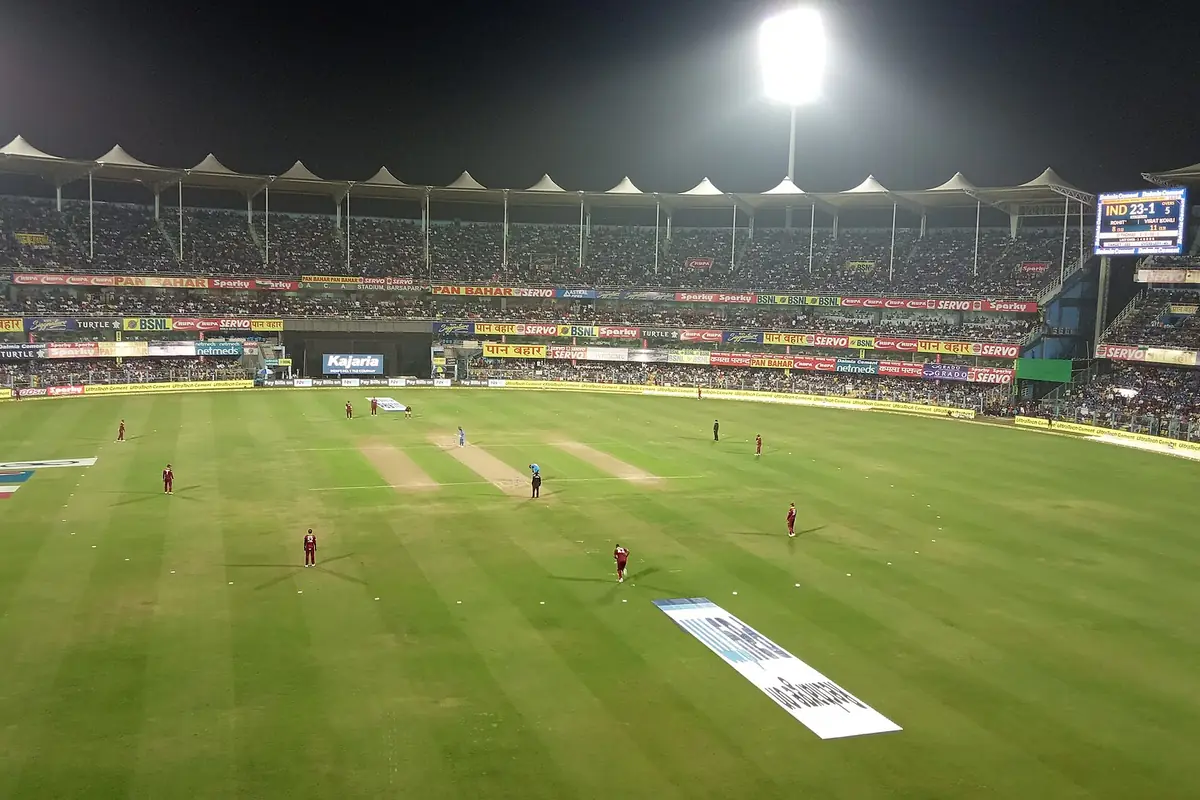 A cricket stadium packed with fans under floodlights at night
