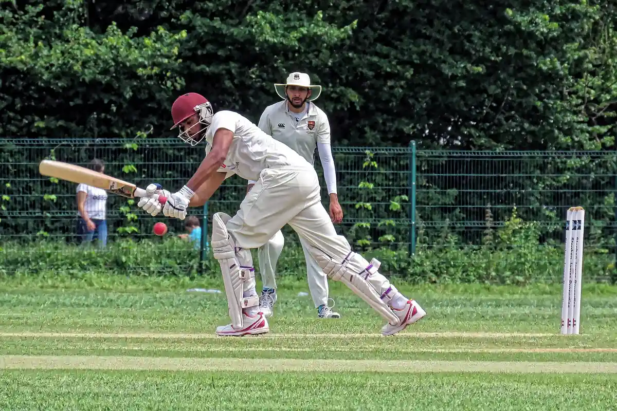 A batter plays a shot during a club cricket match, with the wicketkeeper behind