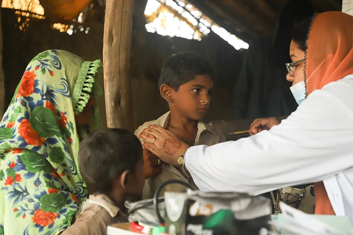 A health worker treating children in a rural Sindh village setting